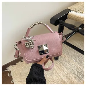 Detailed view of pink small square handbag with silver beaded handle and heart charm.