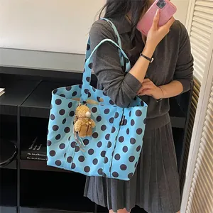 Blue polka dot large tote bag with cute teddy bear keychain held by model