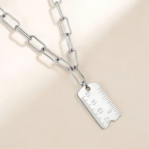 Détail d'un pendentif règle créatif en acier inoxydable sur un collier à chaîne trombone.