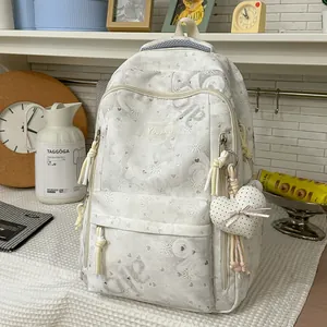Detail view of a white high-capacity backpack with heart patterns and plush pendant.