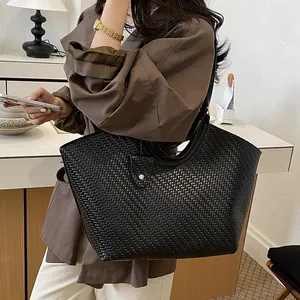 Detail of large black woven tote bag carried as a stylish lifestyle shoulder bag