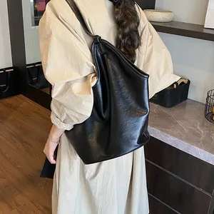 Detailed side view of a large black leather tote bag featuring a slouchy minimalist design