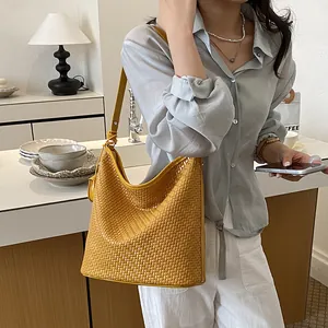 Detailed close-up of a yellow woven hobo bag worn by a model in a stylish interior
