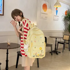 Zaino giapponese giallo con ricamo floreale indossato da una studentessa in un caffè.
