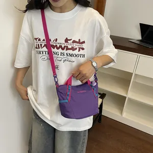 Close-up of a purple and pink crossbody bag with grid texture on a white t-shirt