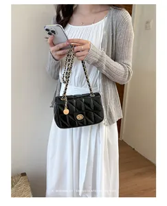 Detailweergave van een zwarte gewatteerde schoudertas met ketting en minimalistische outfit