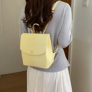 Back view of a model wearing a minimalist light yellow fashion backpack for women