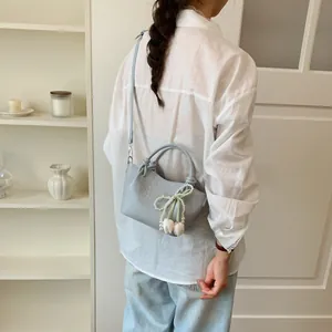 Close-up detail shot of a light blue vintage bucket bag with pearl tulip bow decoration