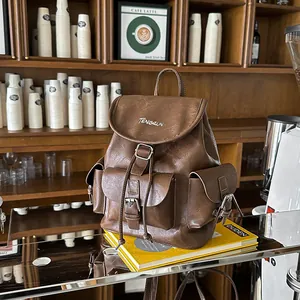 Vintage brown leather backpack displayed in a cafe setting on a yellow book
