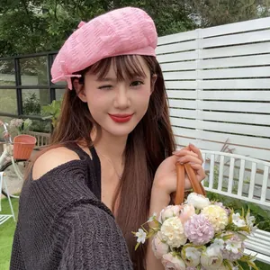 Lifestyle view of a woman wearing a retro pink frayed beret in an outdoor garden setting.