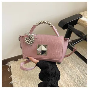 Close-up of pink textured leather handbag with unique metal bead handle and pyramid clasp
