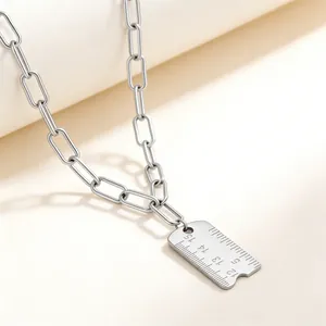 Détail macro d'un pendentif règle créatif en acier inoxydable argenté avec gravures d'échelle