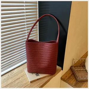 Vista detallada del tejido trenzado del bolso tipo cubo granate con un estilo minimalista.