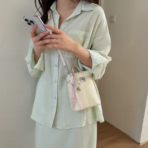Dettaglio di una borsa a tracolla crema per cellulare con un elegante ciondolo a stella