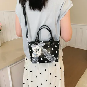 Fashionable black polka dot handbag for women featuring decorative lace and musical note charm