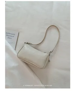 Gros plan d'un sac baguette blanc cassé minimaliste avec texture froissée brillante sur tissu