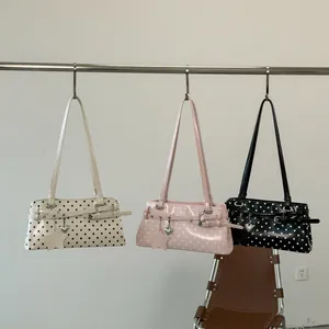 Detailed view of white, pink, and black polka dot underarm bags hanging on a rack.