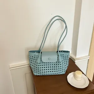 Detailansicht der eleganten Webstruktur einer hellblauen Schultertasche auf Holz.