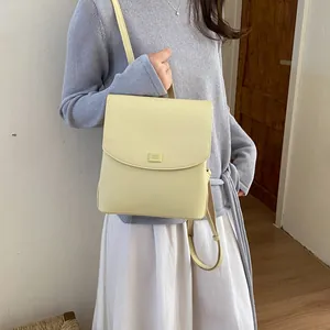 Close-up of a minimalist light yellow leather backpack worn by a model in a casual setting