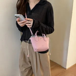 Détail d'un mini sac seau rose avec fermeture à cordon porté par un mannequin
