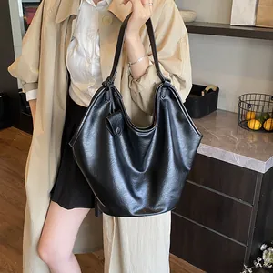 Lifestyle view of a large black faux leather hobo tote bag carried by a model