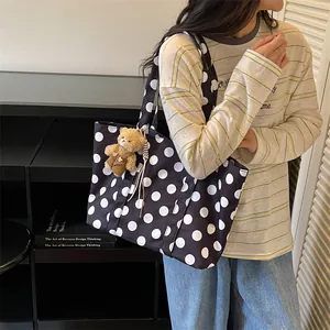 Side view of a stylish large black and white polka dot tote bag with a bear charm