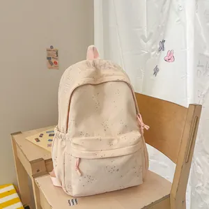 Stylischer hellrosa Rucksack mit Sternenmuster auf einem hölzernen Schülerstuhl-Setup