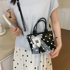 Detail view of a stylish black polka dot handbag with a cute musical note charm