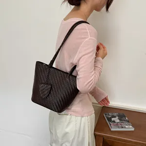 Detailweergave van model met een chique donkerbruine geweven leren tote tas voor werk