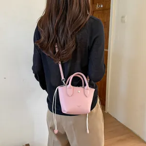 Vue détaillée d'un mini sac seau en cuir rose porté par un mannequin de dos