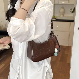 Detailed view of a brown crocodile pattern shoulder bag worn with a white shirt