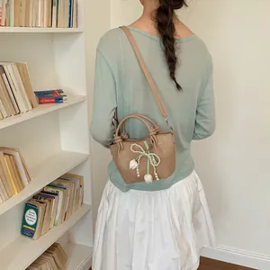 Detail view of a vintage tan bucket bag with pearl bow decoration on model