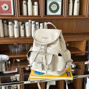 Close-up of a cream faux leather commuter backpack in a cozy cafe setting