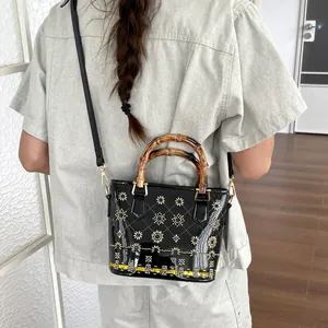 Detail of black retro bucket bag with decorative embroidery and bamboo handles