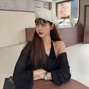 Chic off-white textured beret with frayed edges shown in a stylish cafe setting