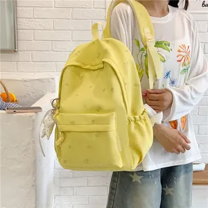Yellow floral student backpack with large capacity and fresh design worn by a model.