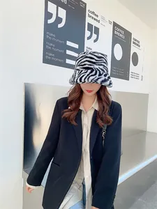 Gros plan d'une femme portant un bob en peluche à motif zébré et un blazer noir.