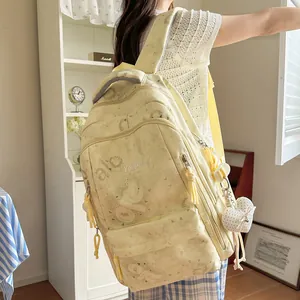 Woman wearing a large pale yellow casual backpack with heart charm in a bright room