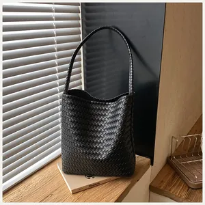 Primer plano de un bolso de cubo negro tejido a mano en estilo minimalista
