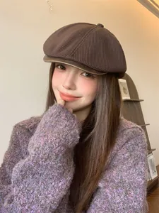 Detailed view of a vintage brown knitted newsboy hat styled by a model in a cozy indoor setting