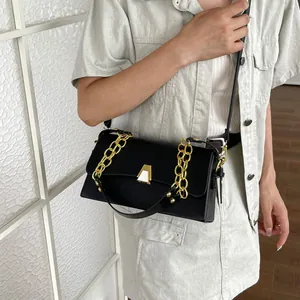 Detail view of a black chic crossbody bag with elegant gold chain and hardware accent