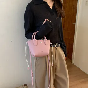 Mini sac seau rose avec cordon de serrage présenté par un mannequin en tenue.