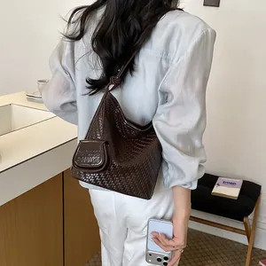 Detailed macro view of a high-end brown woven shoulder bucket bag with mini pouch