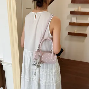 Detailed shot of a pink polka dot cylinder handbag featuring a unique silver star charm