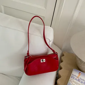 Élégant sac baguette rouge style français avec ferrures argentées sur canapé blanc