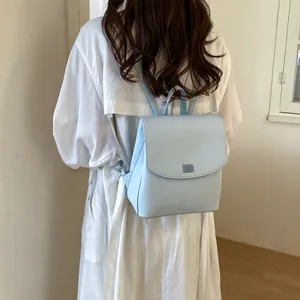 Stylish light blue minimalist backpack for women shown on model wearing white shirt