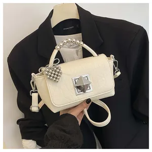 Detailed view of cream-white textured small square handbag with metallic bead handle