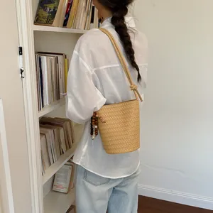 Minimalistische braune geflochtene Beuteltasche mit Perlenanhänger am Modell präsentiert