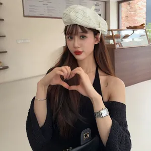Model wearing a stylish vintage-style beige textured beret hat in a cozy cafe setting