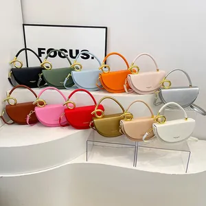 Umhängetaschen in Sattelform in vielen Farben mit markanten goldfarbenen Ringdetails.